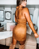 A person wearing a brown suede mini dress with a flared skirt, posing indoors.