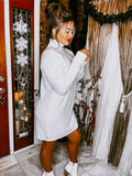Model wearing a white cowl neck tunic sweater dress with white boots.