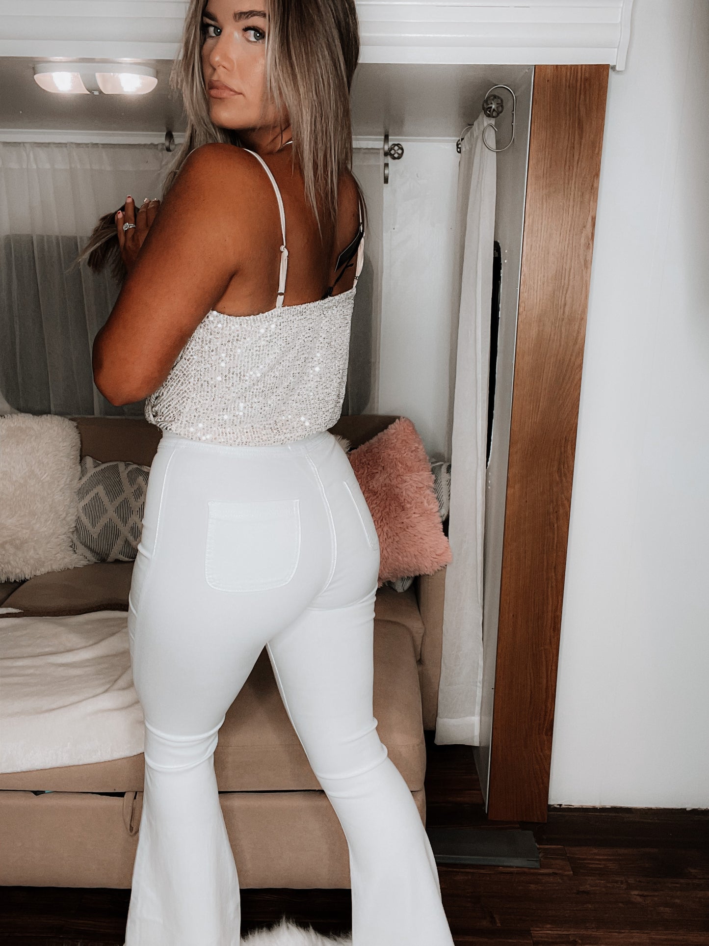 Side view of white bell-bottom jeans displaying the high-rise waist and wide-leg silhouette with retro styling