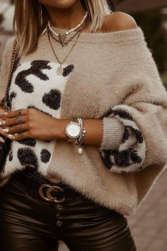 A woman wearing a crew neck sweater with leopard print pattern, and black jeans