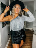 Model wearing a black faux leather skirt with a fringe design, paired with a gray crop top and a black hat.