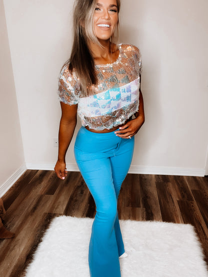 A woman wearing a blue, checkered sea-inspired top with three-quarter sleeves and a round neckline, paired with blue jeans.