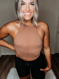 A person wearing a brown backless top with a v-neck design.